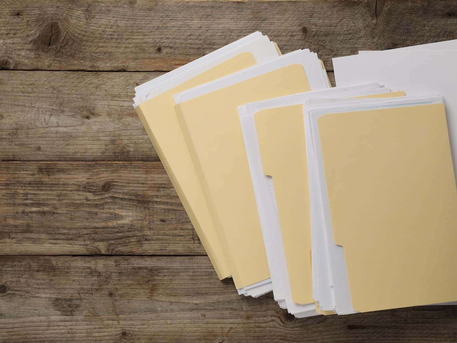 Manila folders stacked on wood.